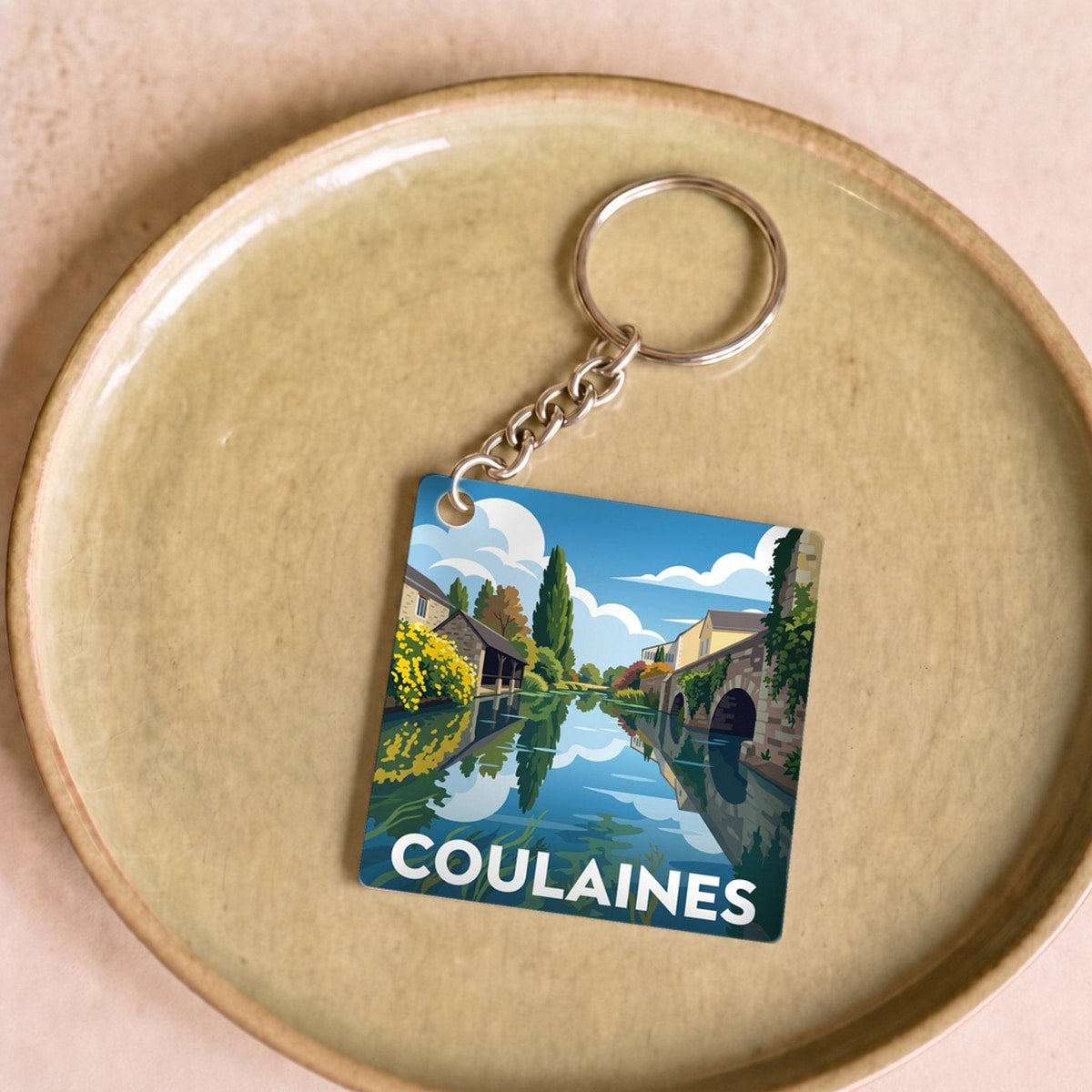 Porte-clés souvenir de la ville de Coulaines avec une illustration stylisée.