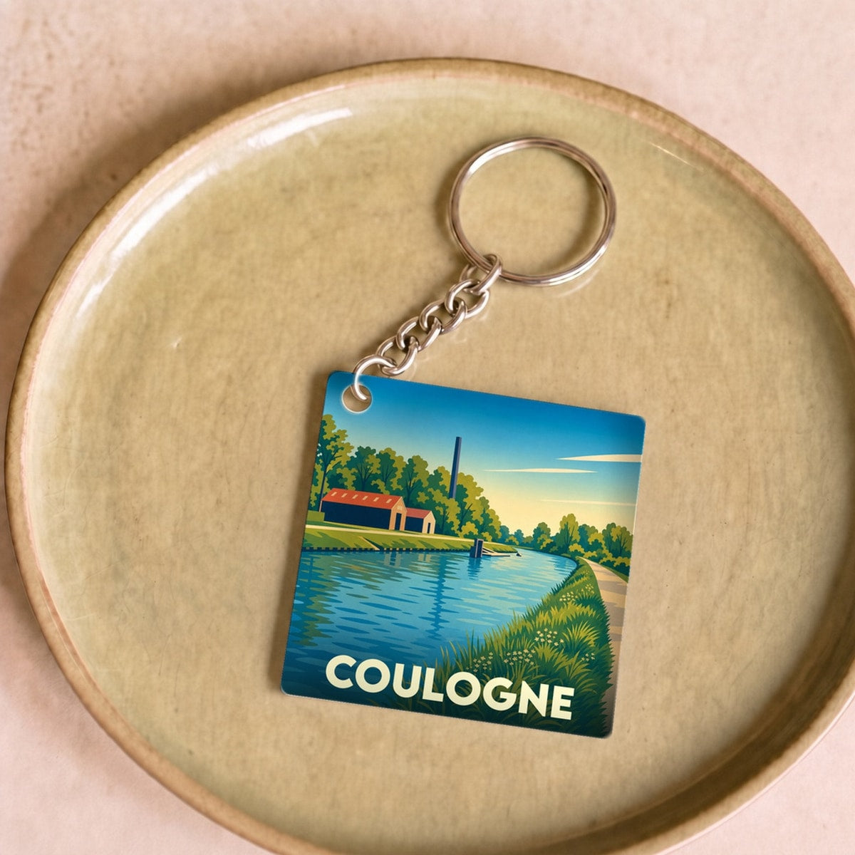 Porte-clés souvenir de la ville de Coulogne avec une illustration stylisée de son canal.