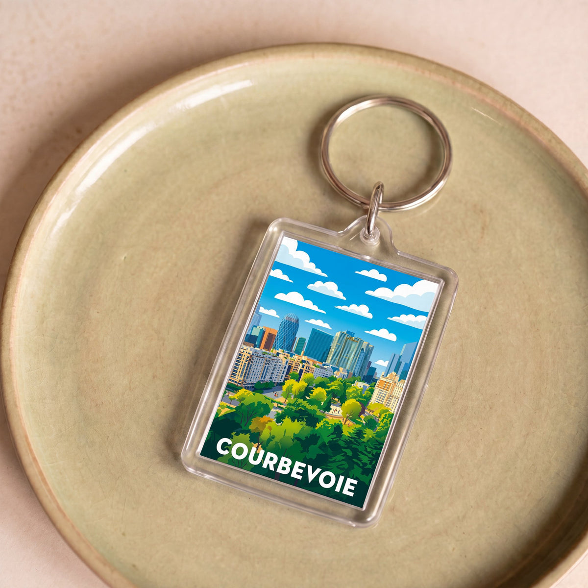 Porte-clés souvenir de la ville de Courbevoie avec une illustration stylisée.