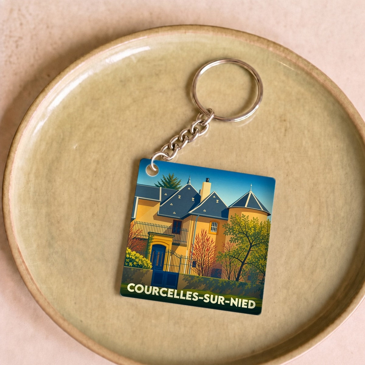 Porte-clés souvenir de la ville de Courcelles-sur-Nied avec une illustration stylisée.