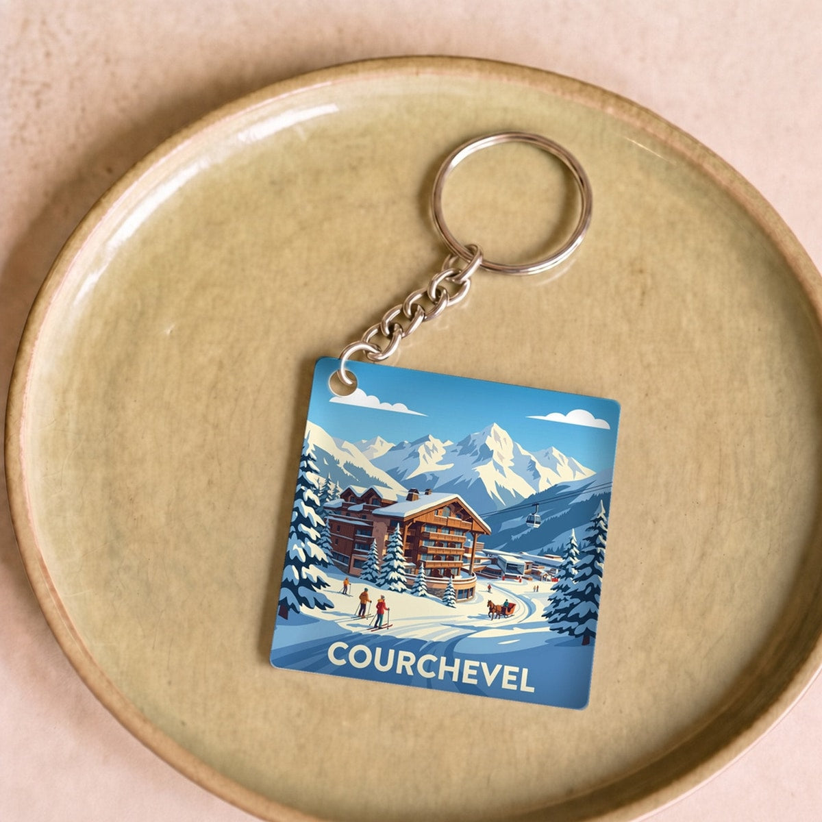 Porte-clés souvenir de la ville de Courchevel avec une illustration stylisée d'un paysage de montagne enneigé.