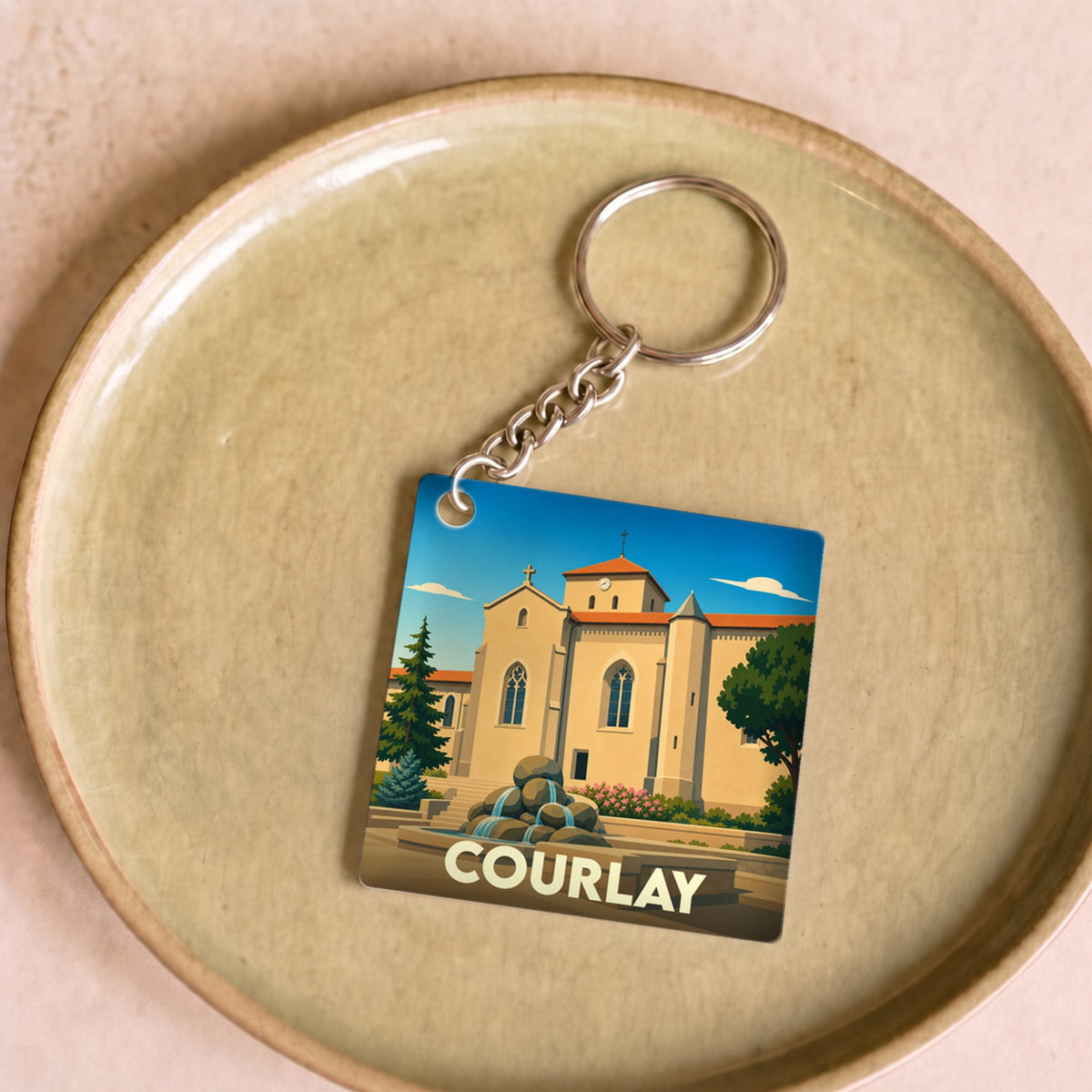 Porte-clés souvenir de la ville de Courlay avec une illustration stylisée d'une église et d'une fontaine.