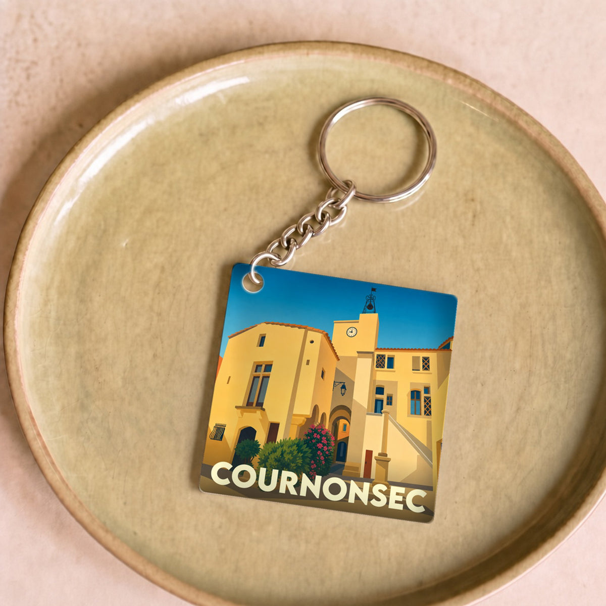 Porte-clés souvenir de la ville de Cournonsec avec une illustration stylisée.