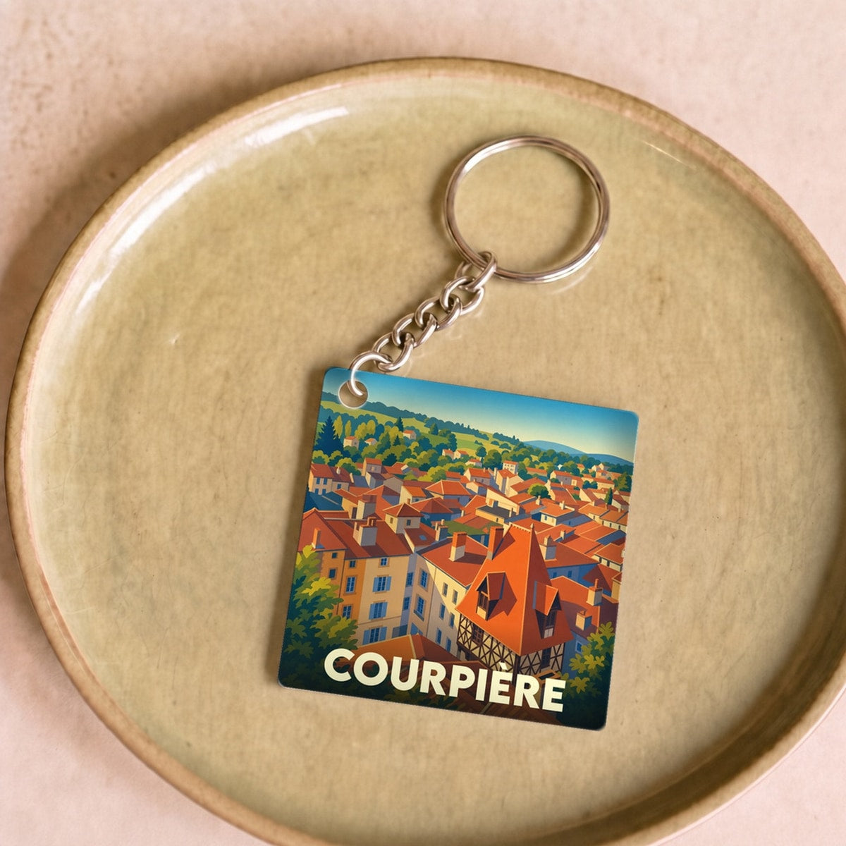 Porte-clés souvenir de la ville de Courpière avec une illustration stylisée.
