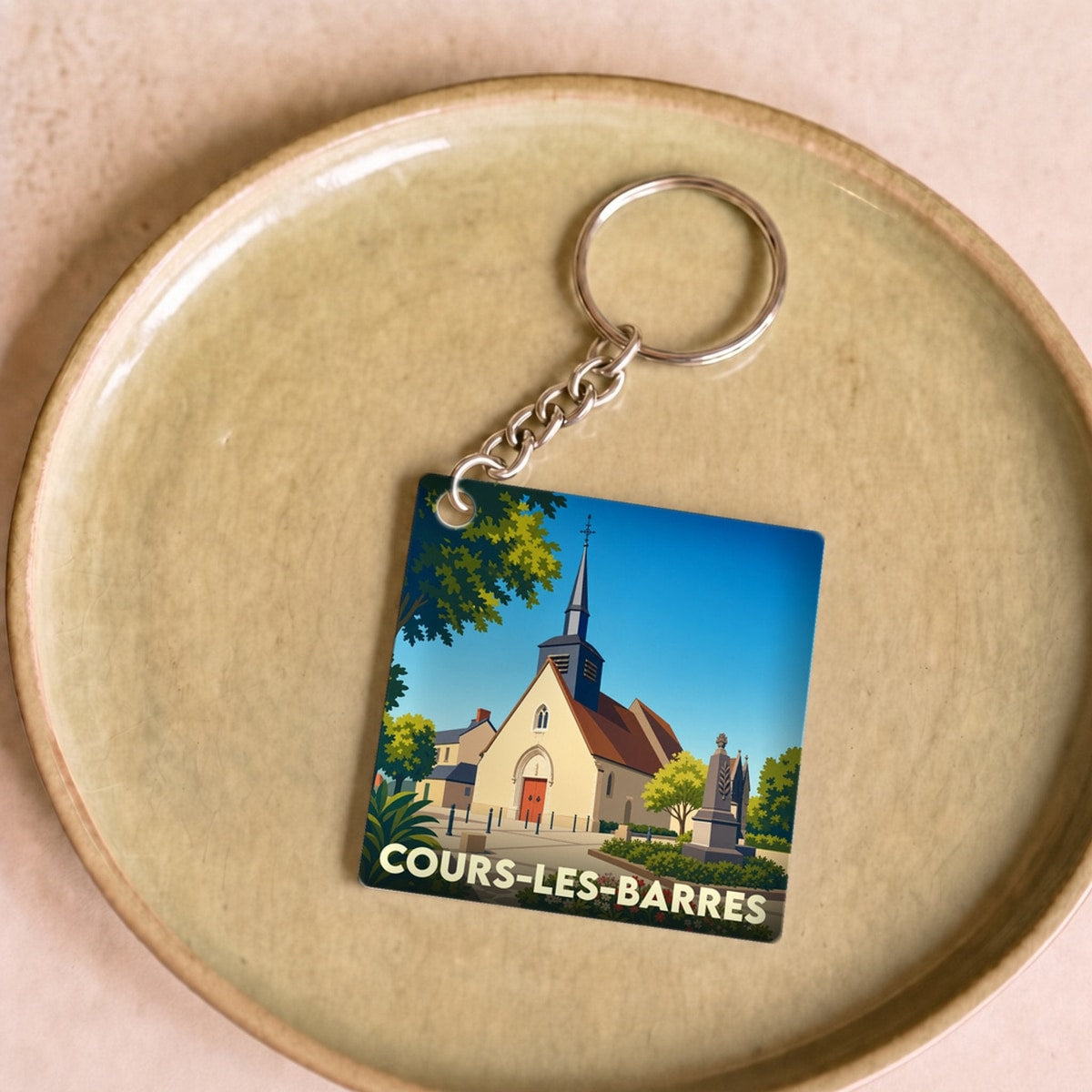 Porte-clés souvenir de la ville de Cours-les-Barres avec une illustration stylisée de son église.