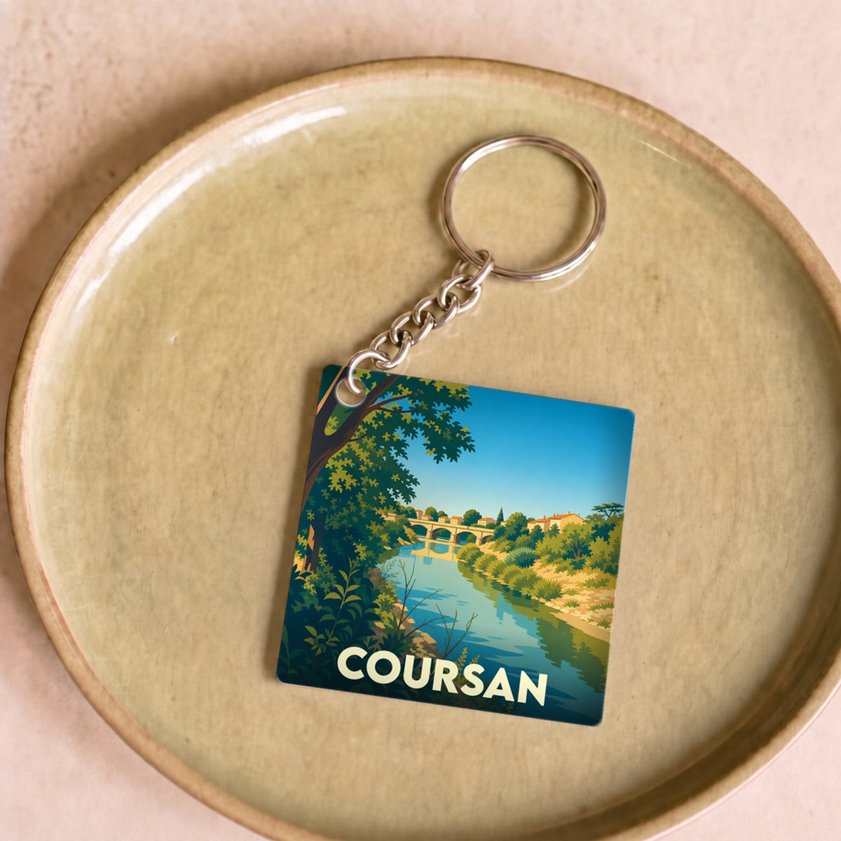 Porte-clés souvenir de la ville de Coursan avec une illustration stylisée représentant un pont sur une rivière.