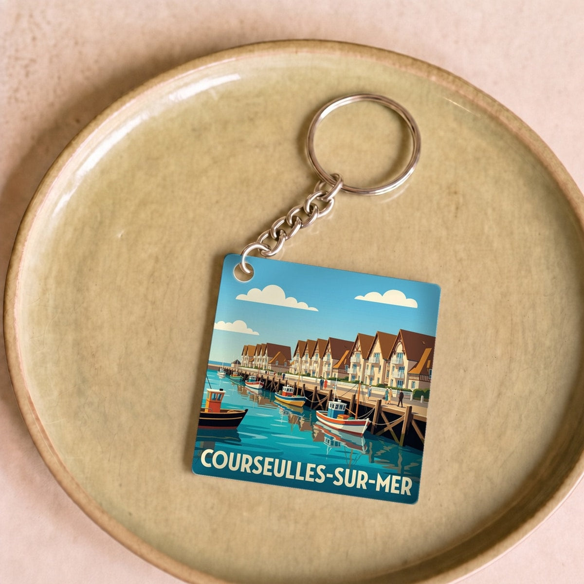 Porte-clés souvenir de la ville de Courseulles-sur-Mer avec une illustration stylisée.