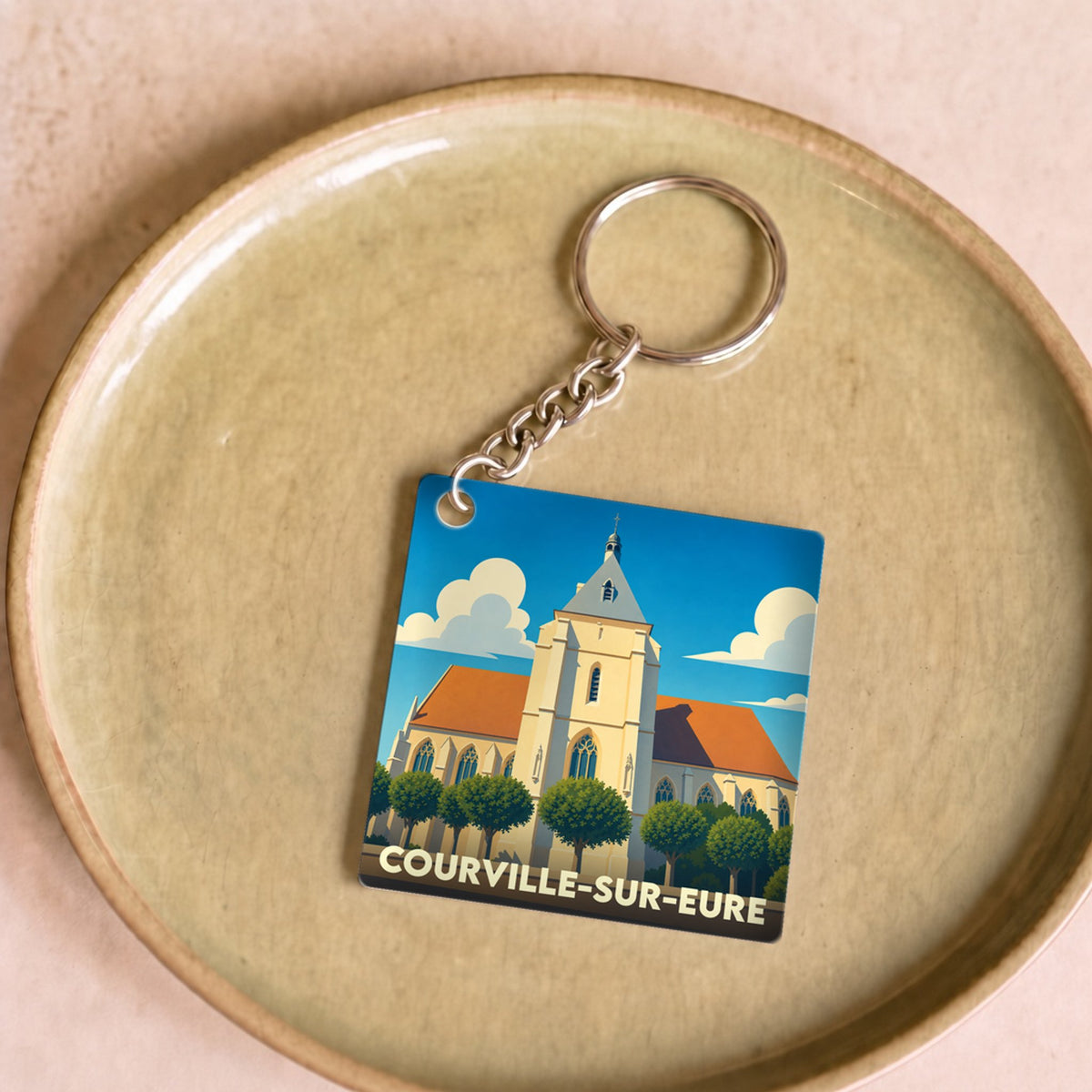 Porte-clés souvenir de la ville de Courville-sur-Eure avec une illustration stylisée de son église.