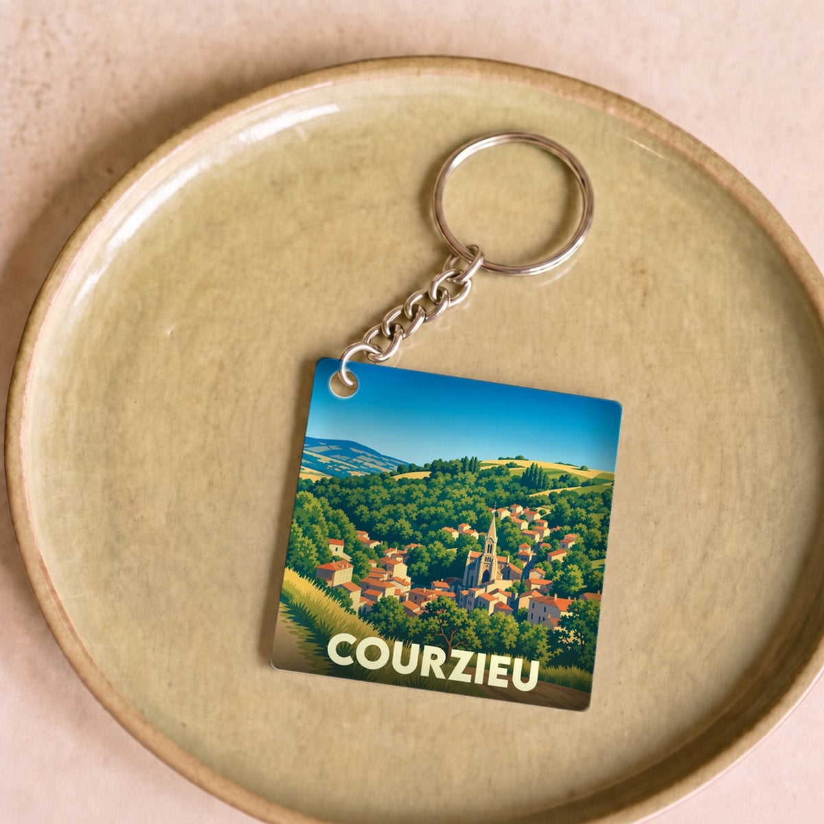 Porte-clés souvenir de la ville de Courzieu avec une illustration stylisée de son paysage vallonné.