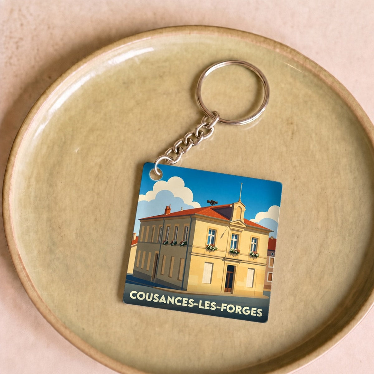 Porte-clés souvenir de la ville de Cousances-les-Forges avec une illustration stylisée.