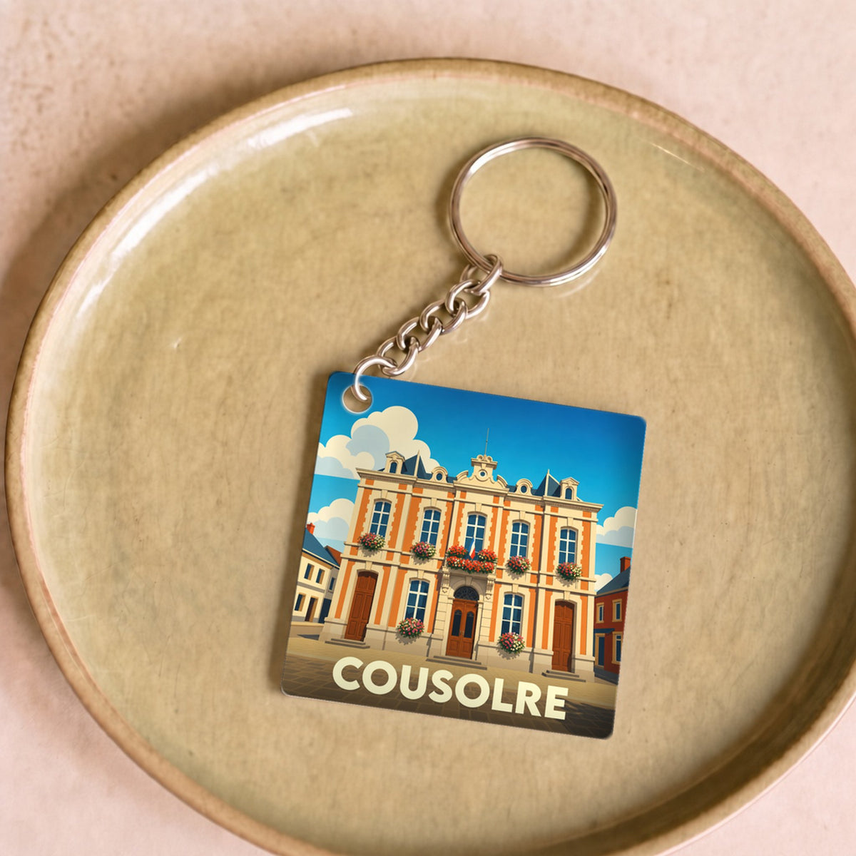 Porte-clés souvenir de la ville de Cousolre avec une illustration stylisée de son hôtel de ville.