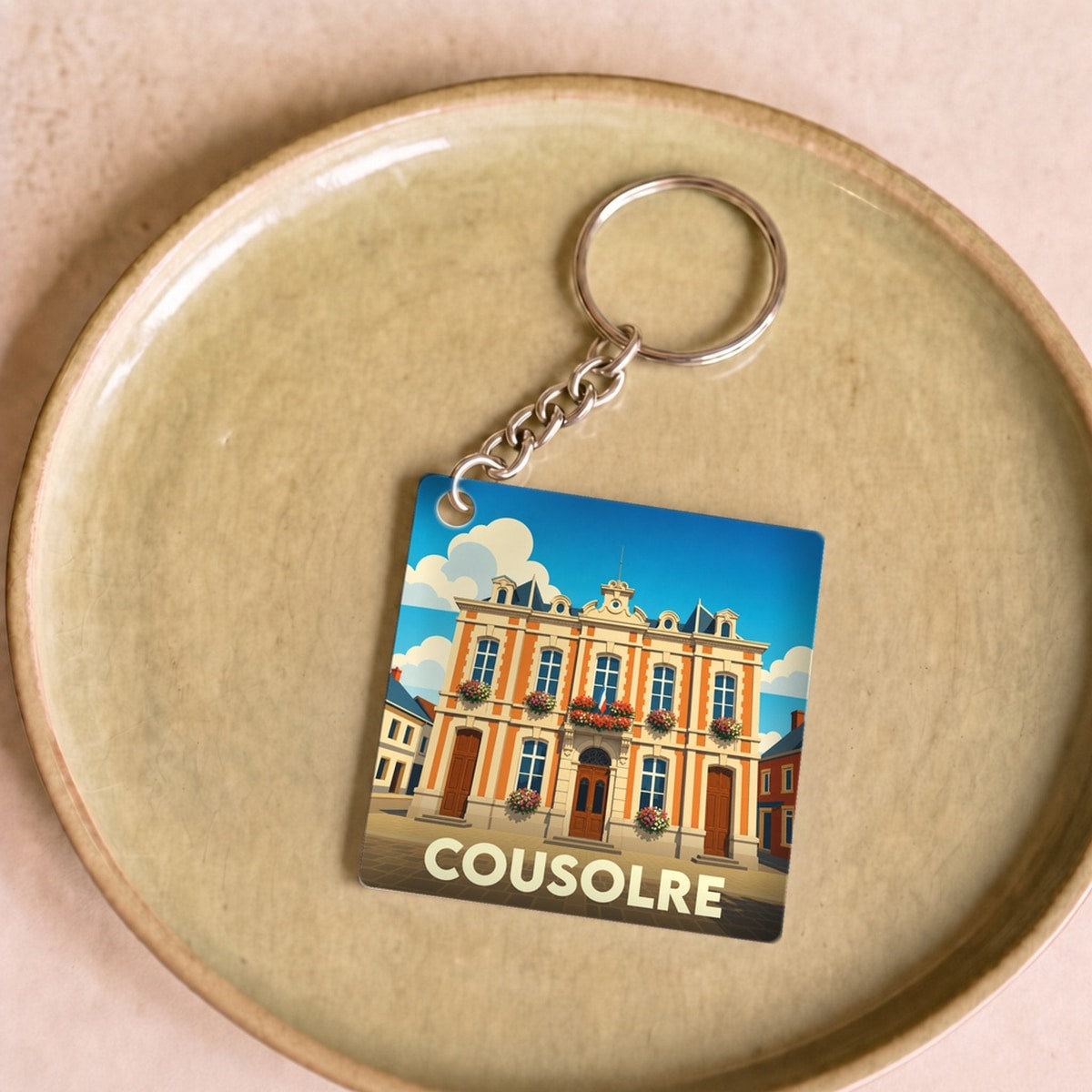 Porte-clés souvenir de la ville de Cousolre avec une illustration stylisée de son hôtel de ville.