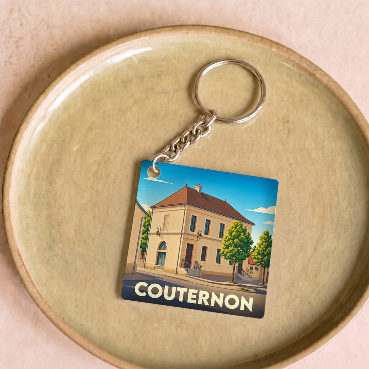 Porte-clés souvenir de la ville de Couternon avec une illustration stylisée d'un bâtiment historique.