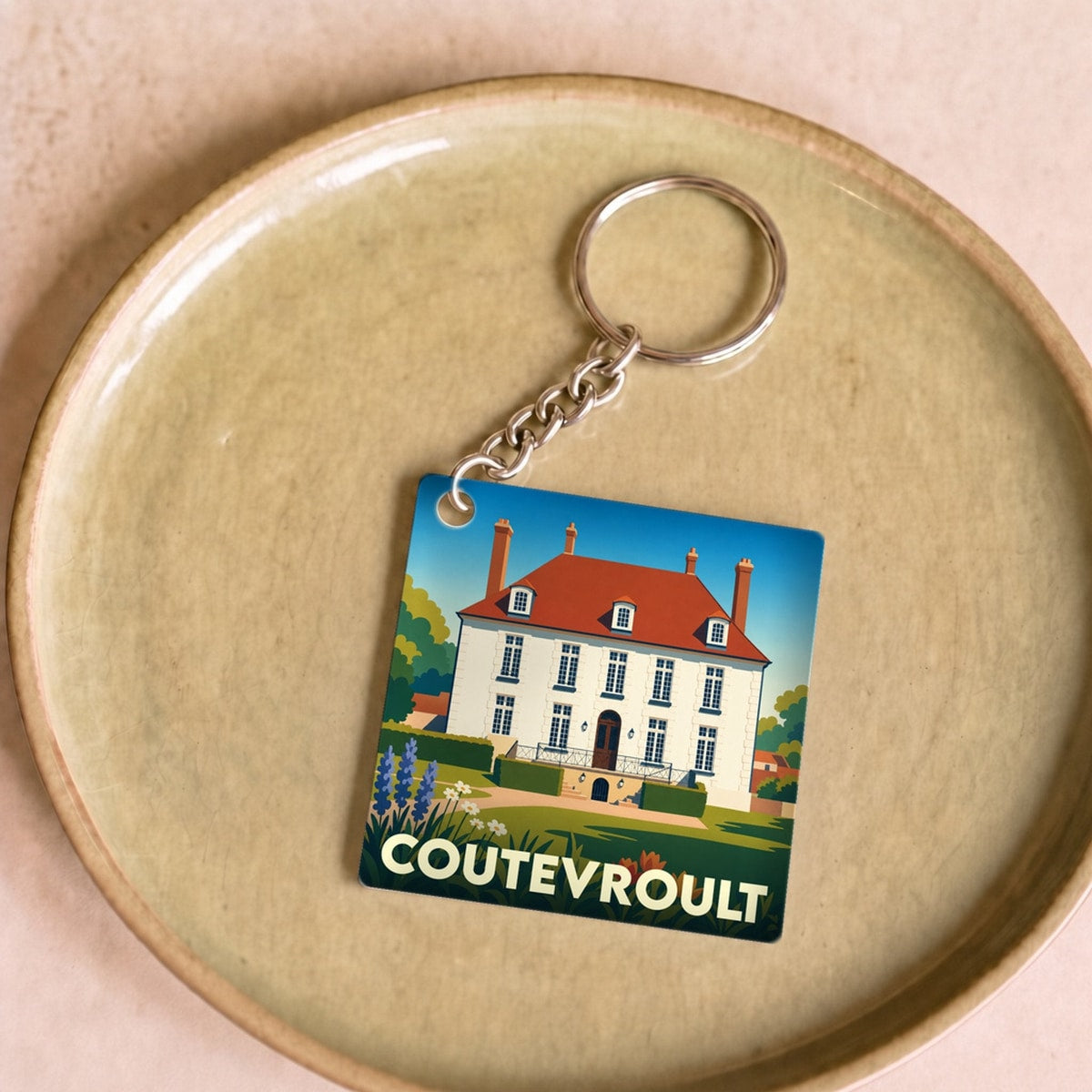 Porte-clés souvenir de la ville de Coutevroult avec une illustration stylisée d'une demeure bourgeoise.