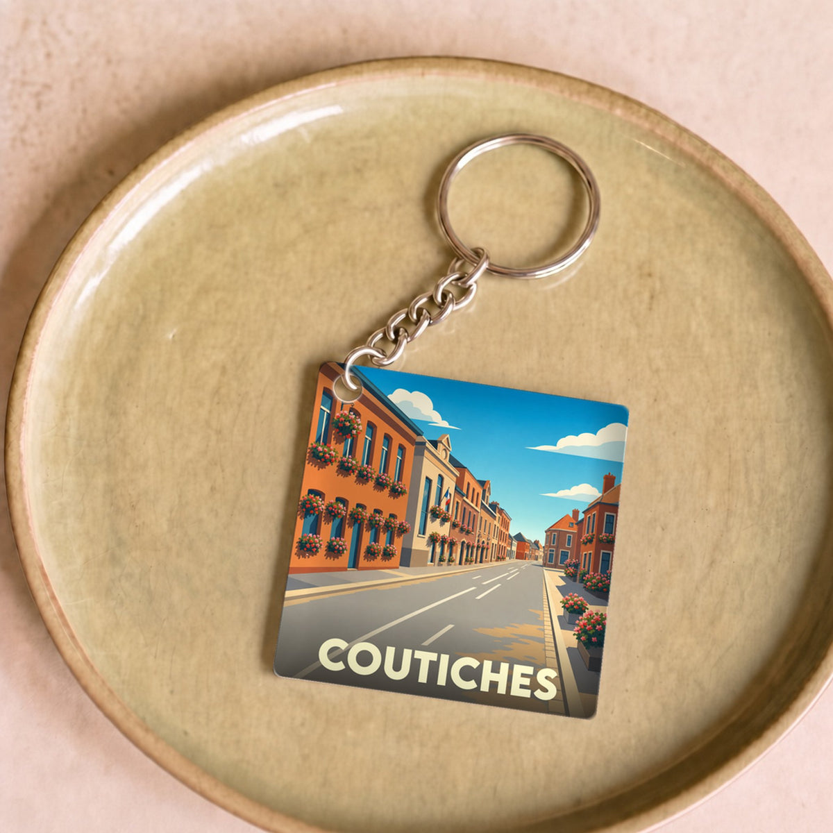 Porte-clés souvenir de la ville de Coutiches avec une illustration stylisée d'une rue colorée.