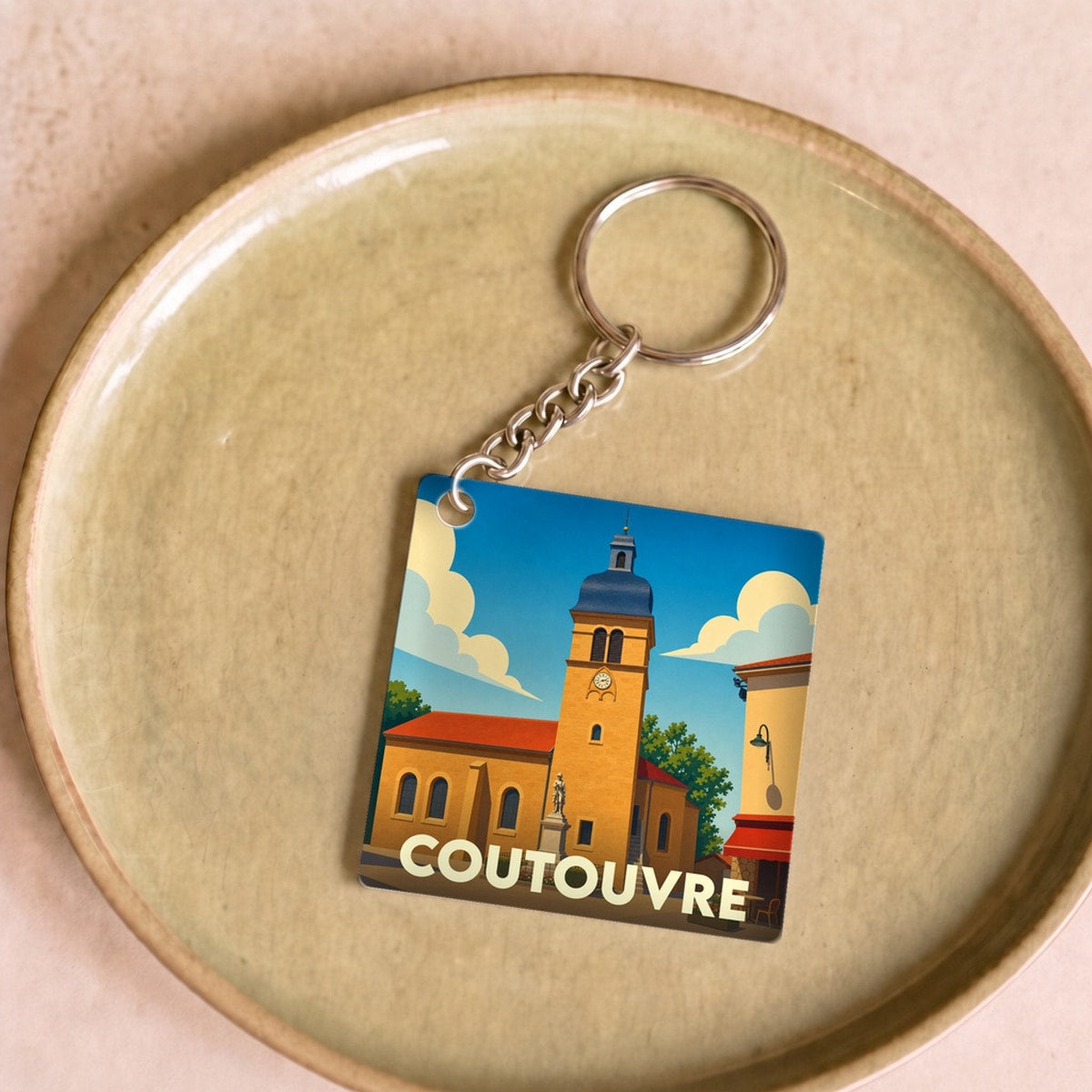 Porte-clés souvenir de la ville de Coutouvre avec une illustration stylisée de son église.