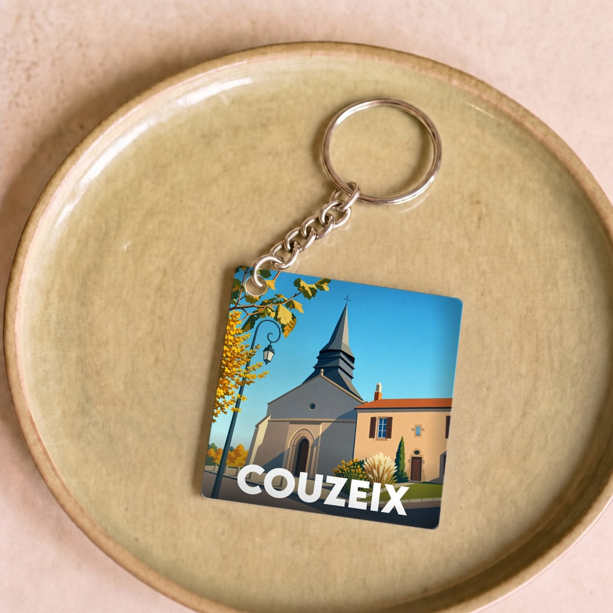 Porte-clés souvenir de la ville de Couzeix avec une illustration stylisée.