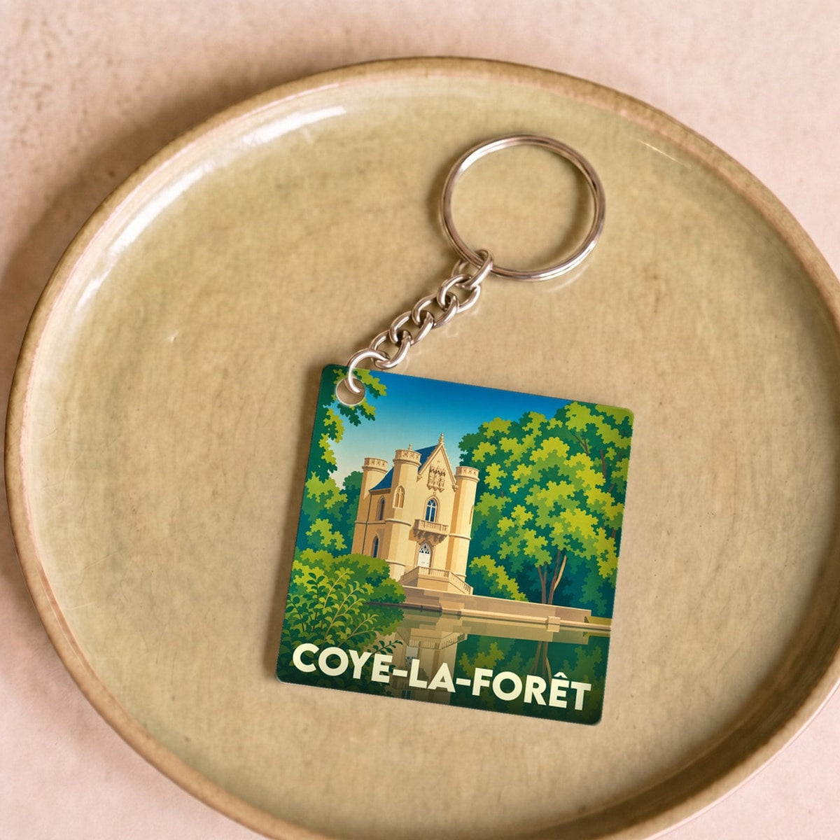 Porte-clés souvenir de la ville de Coye-la-Forêt avec une illustration stylisée de son château.