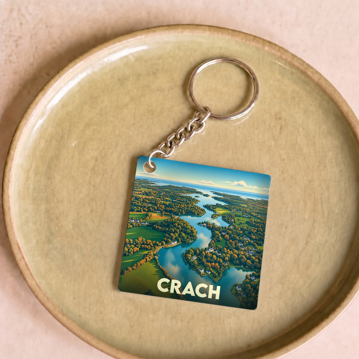 Porte-clés souvenir de la ville de Crach avec une illustration stylisée d'un paysage côtier vu du ciel.