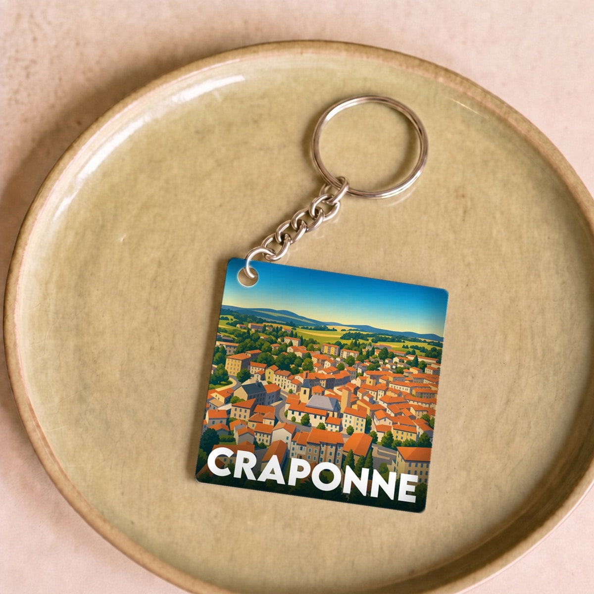 Porte-clés souvenir de la ville de Craponne avec une illustration stylisée de ses paysages.