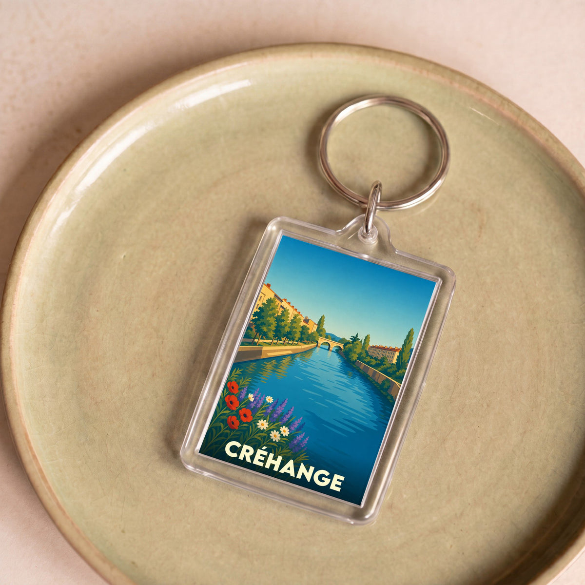 Porte-clés souvenir de la ville de Créhange avec une illustration stylisée d'un canal et d'un pont.