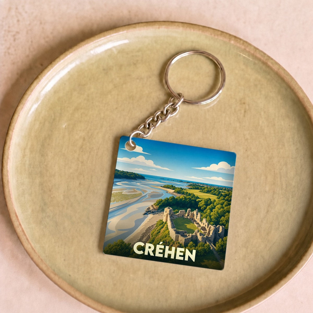 Porte-clés souvenir de la ville de Créhen avec une illustration stylisée de son paysage côtier et de son château.