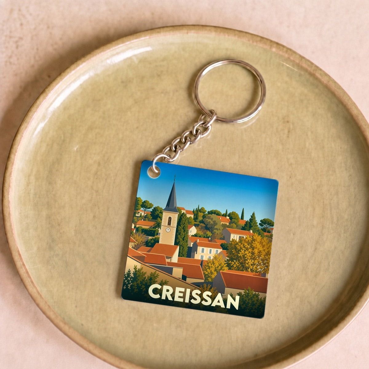 Porte-clés souvenir de la ville de Creissan avec une illustration stylisée.