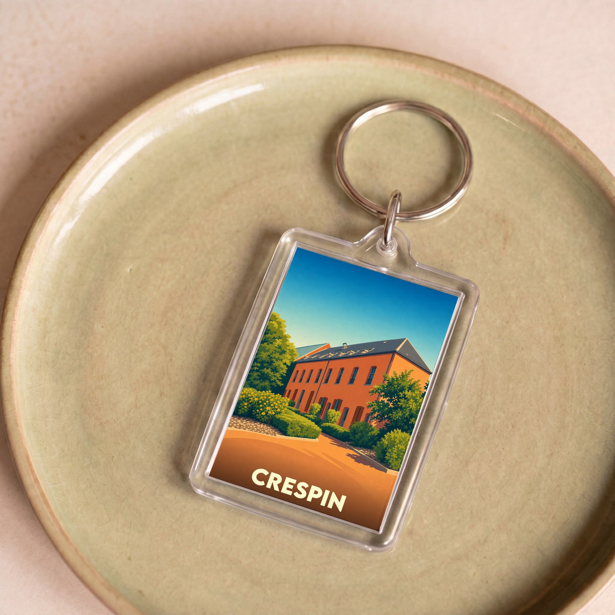 Porte-clés souvenir de la ville de Crespin avec une illustration stylisée d'un bâtiment en briques.