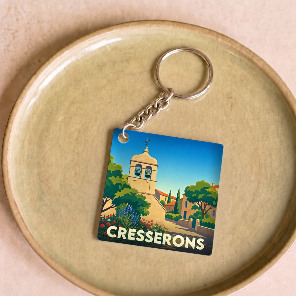 Porte-clés souvenir de la ville de Cresserons avec une illustration stylisée de son clocher.