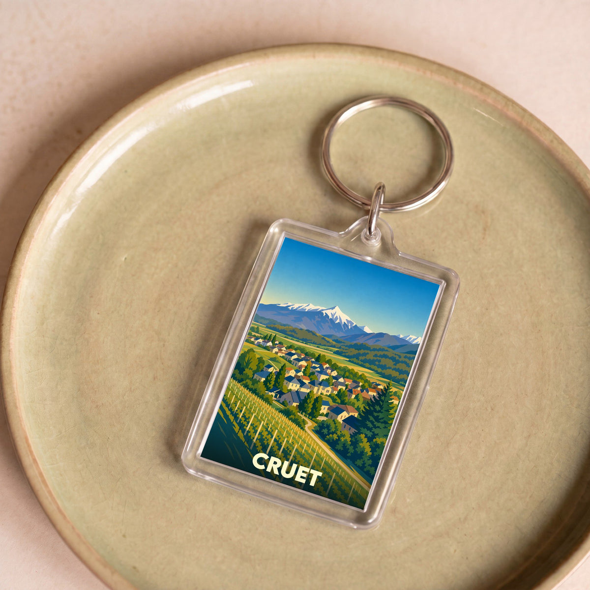 Porte-clés souvenir de la ville de Cruet avec une illustration stylisée de son paysage alpin et ses vignobles.