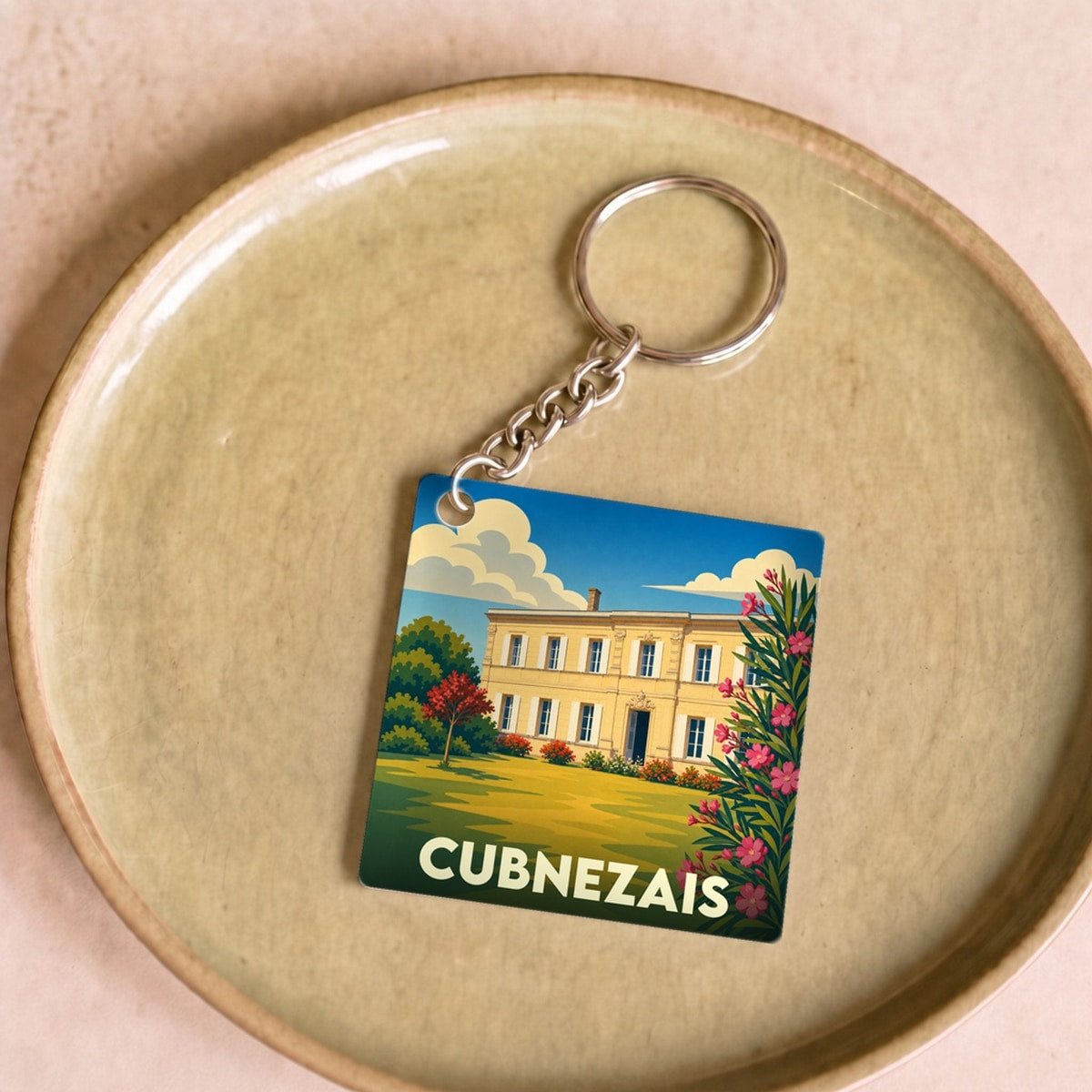 Porte-clés souvenir de la ville de Cubnezais avec une illustration stylisée d'un domaine viticole.