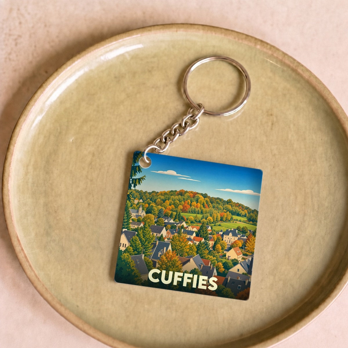 Porte-clés souvenir de la ville de Cuffies avec une illustration stylisée d'un paysage automnal.