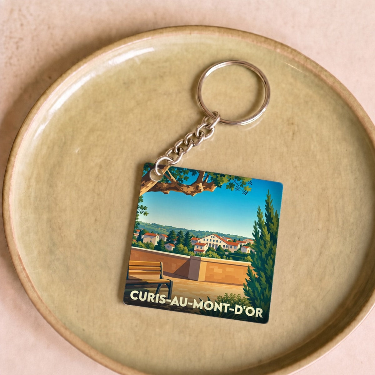 Porte-clés souvenir de la ville de Curis-au-Mont-d'Or avec une illustration stylisée d'un paysage local.