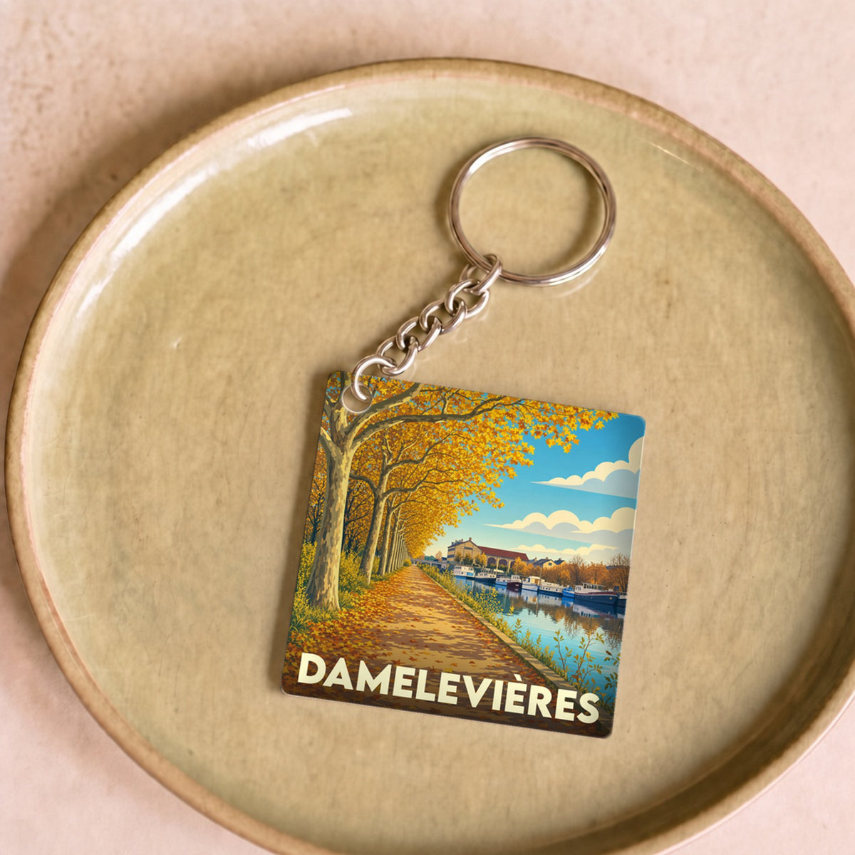 Porte-clés souvenir de la ville de Damelevières avec une illustration stylisée d'un canal en automne.
