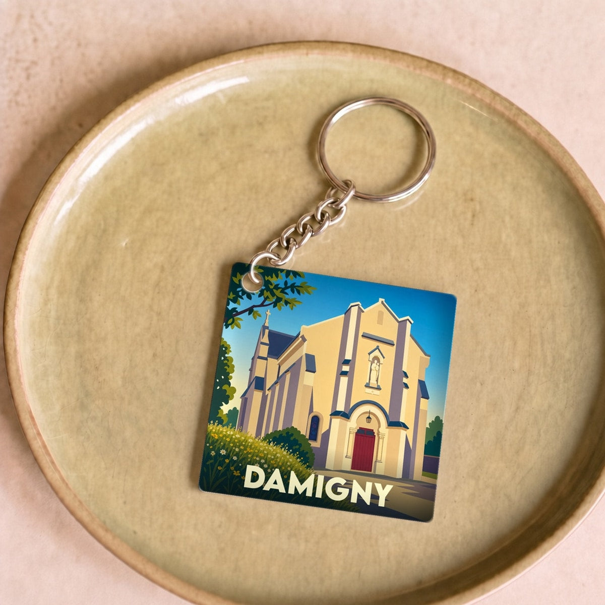 Porte-clés souvenir de la ville de Damigny avec une illustration stylisée de son église.