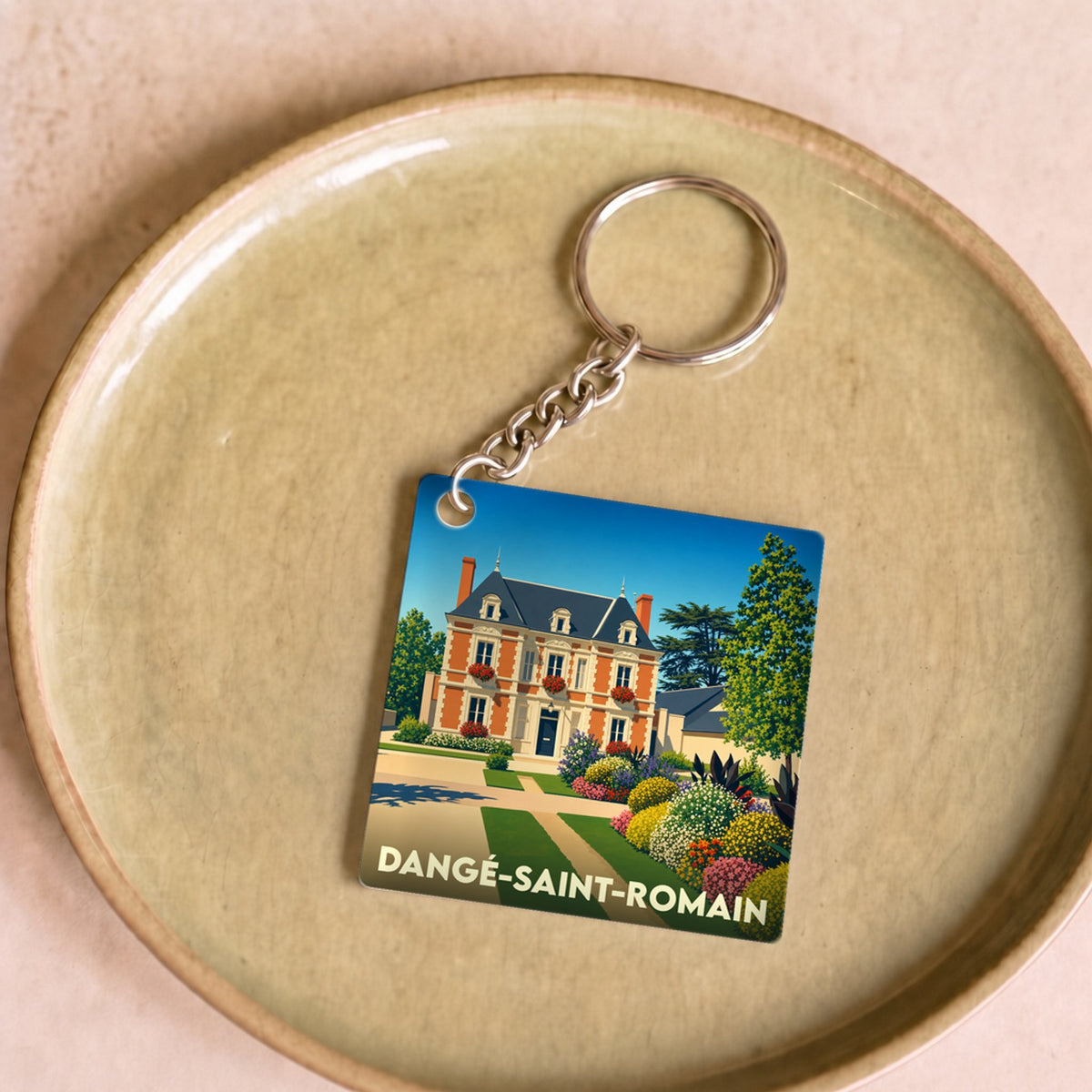 Porte-clés souvenir de la ville de Dangé-Saint-Romain avec une illustration stylisée d'un manoir fleuri.