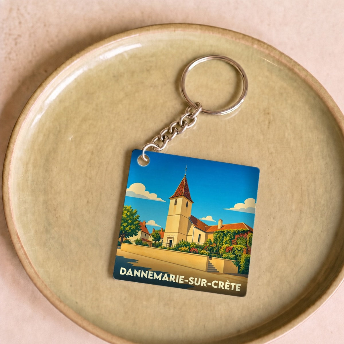 Porte-clés souvenir de la ville de Dannemarie-sur-Crète avec une illustration stylisée de son église.