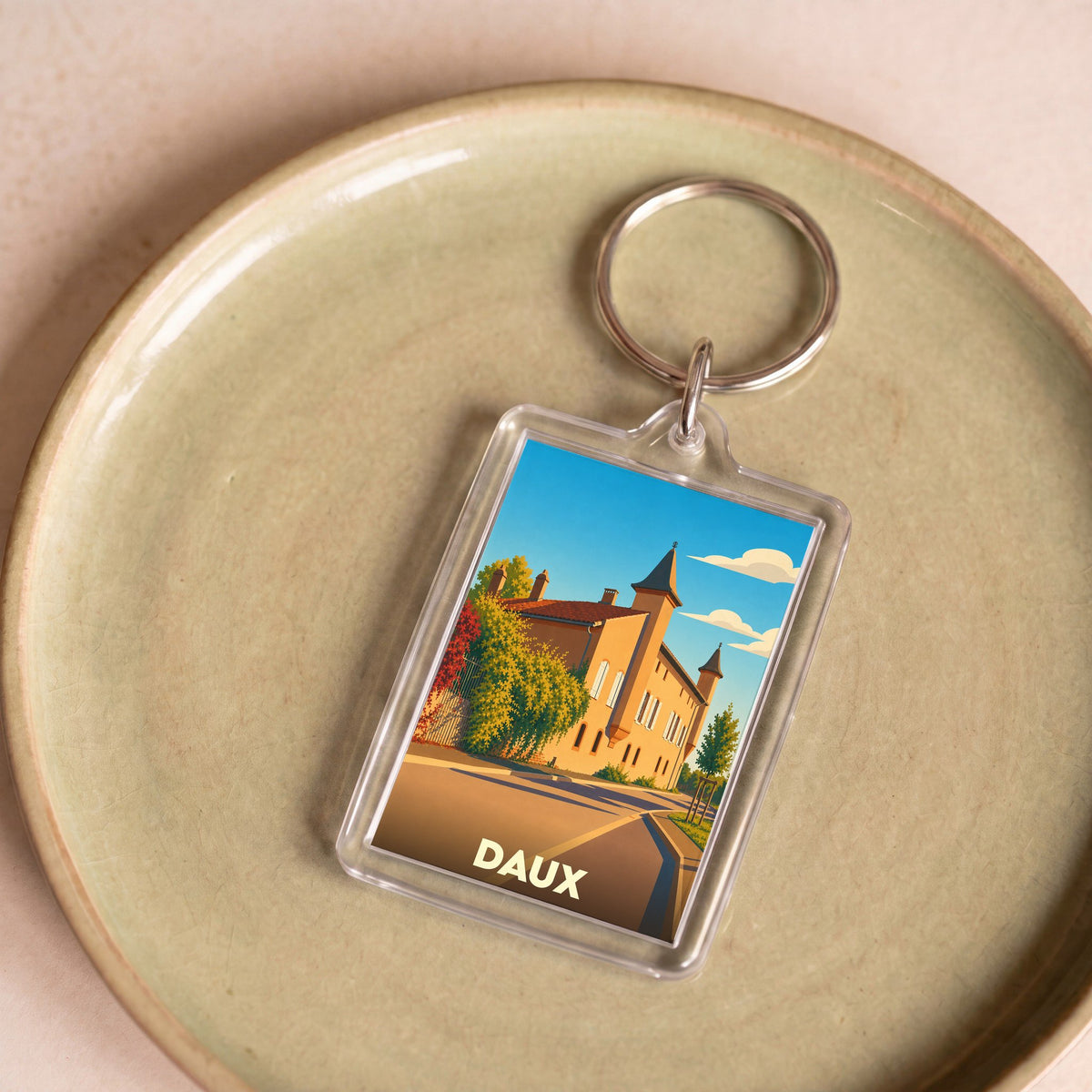 Porte-clés souvenir de la ville de Daux avec une illustration stylisée de son patrimoine.