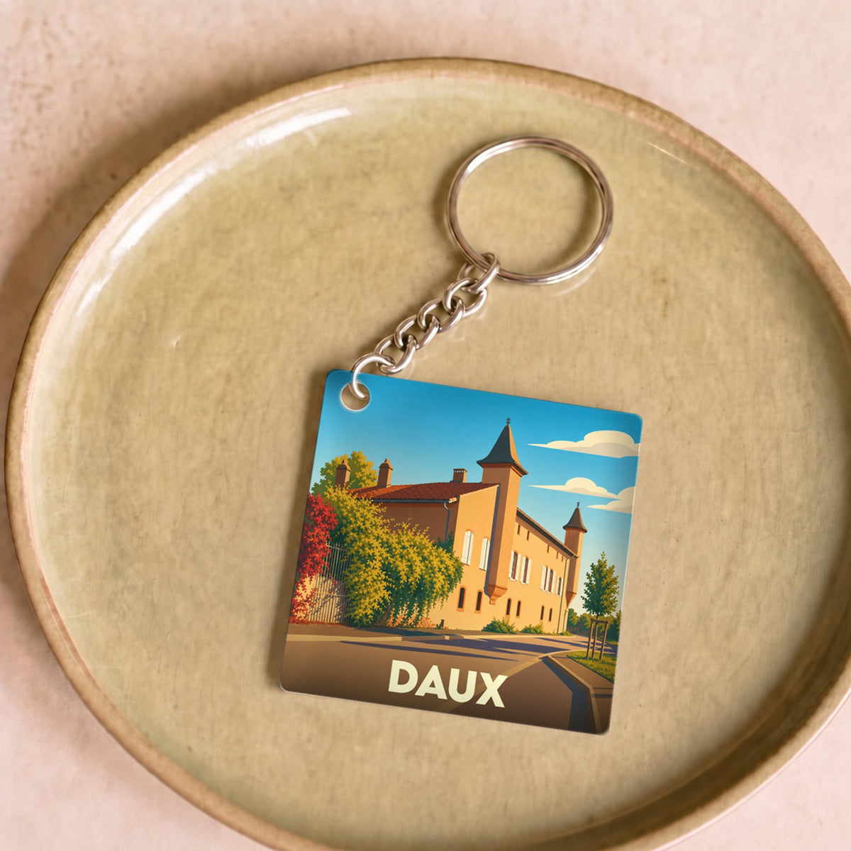 Porte-clés souvenir de la ville de Daux avec une illustration stylisée de son patrimoine.