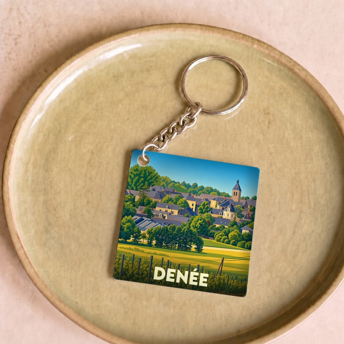 Porte-clés souvenir de la ville de Denée avec une illustration stylisée.