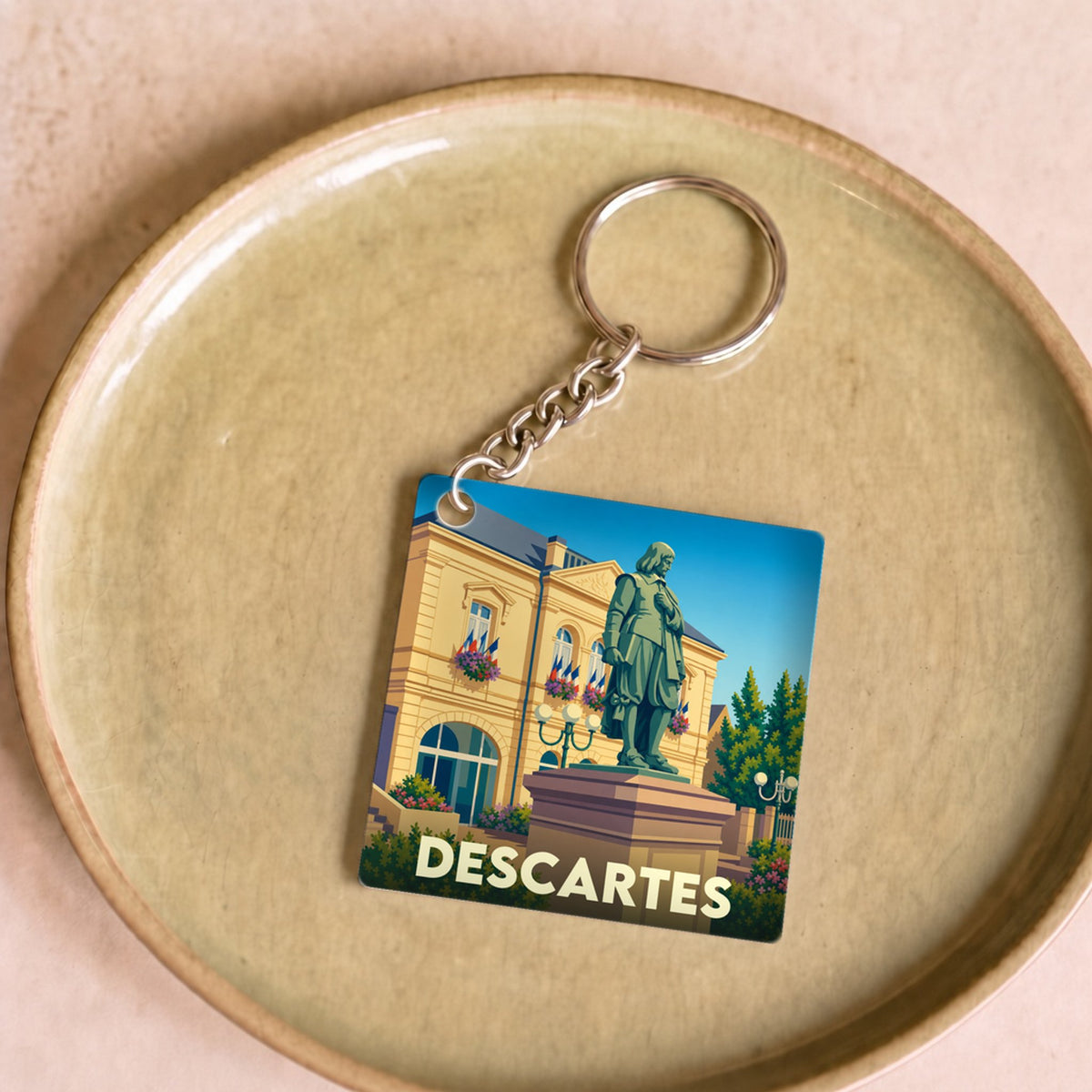 Porte-clés souvenir de la ville de Descartes avec une illustration stylisée de sa statue et de l'hôtel de ville.