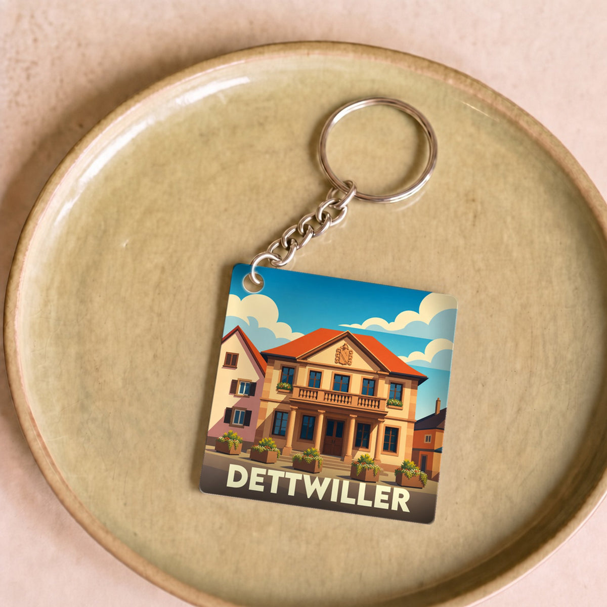 Porte-clés souvenir de la ville de Dettwiller avec une illustration stylisée de son architecture.
