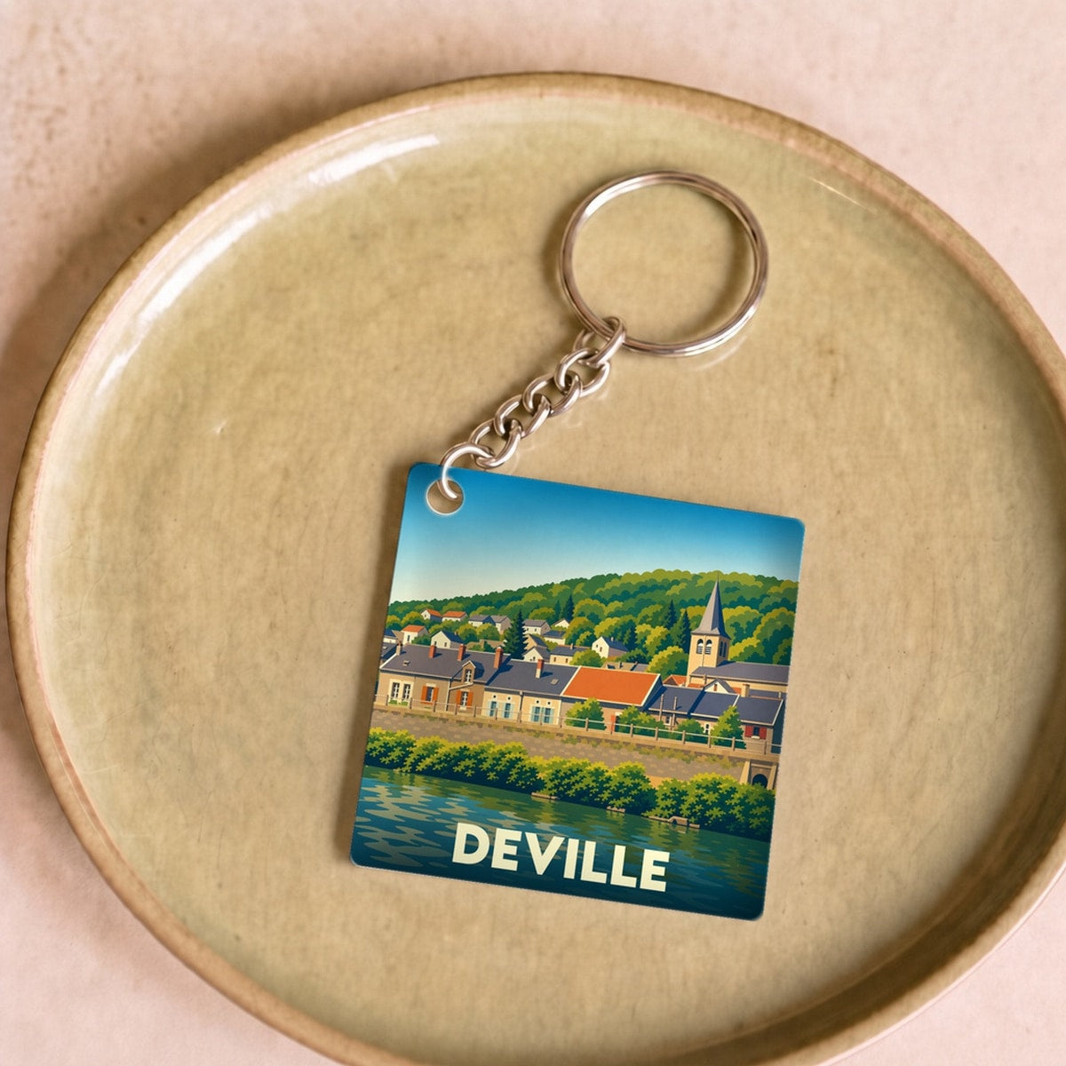 Porte-clés souvenir de la ville de Deville avec une illustration stylisée d'un paysage urbain au bord de l'eau.