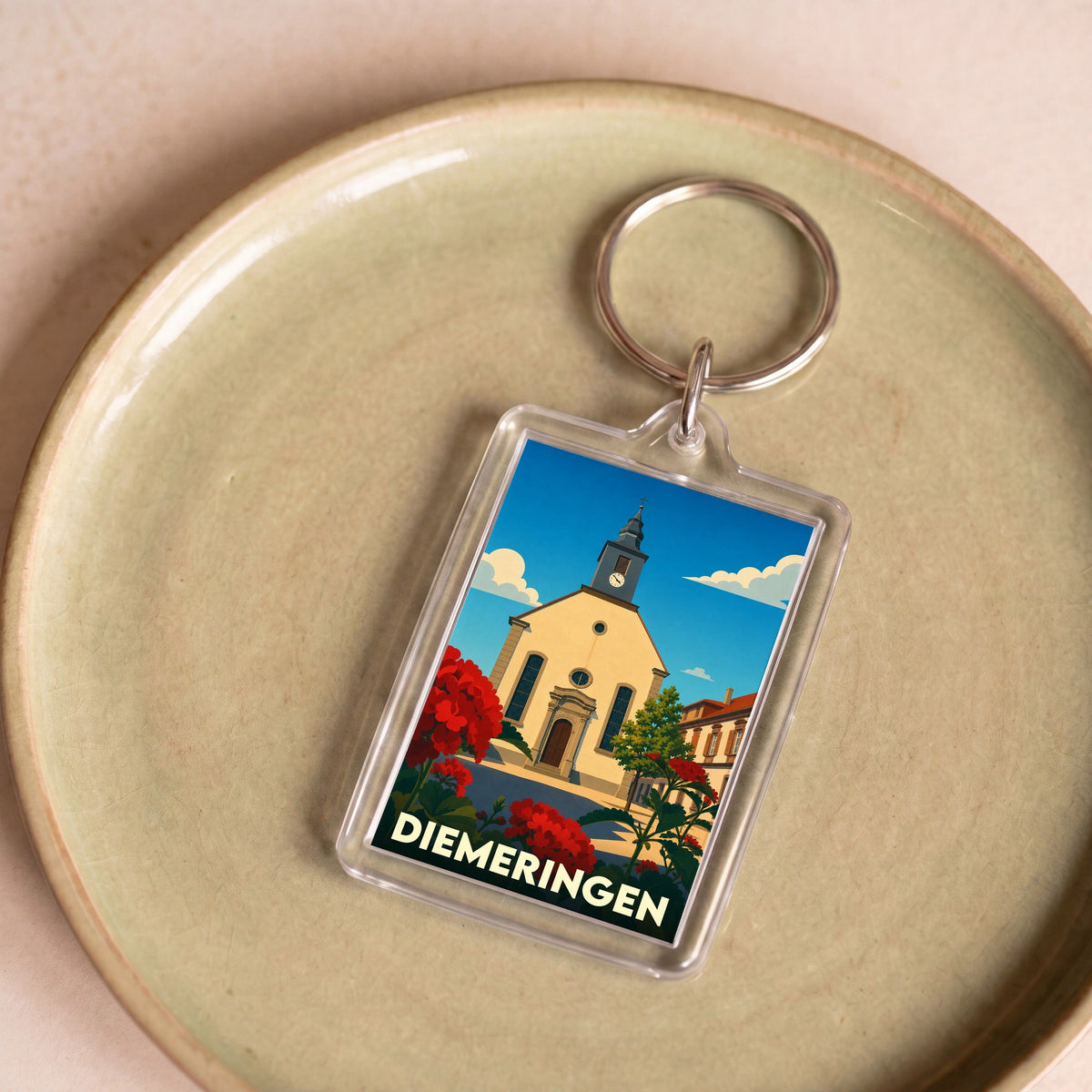 Porte-clés souvenir de la ville de Diemeringen avec une illustration stylisée de son église et de fleurs rouges.