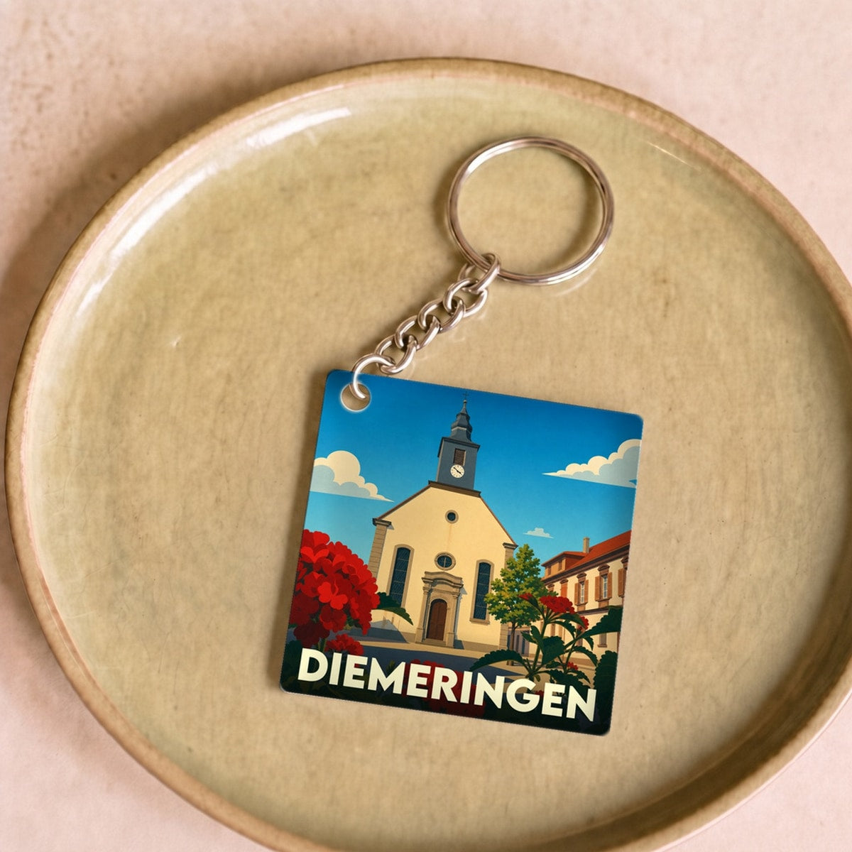 Porte-clés souvenir de la ville de Diemeringen avec une illustration stylisée de son église et de fleurs rouges.