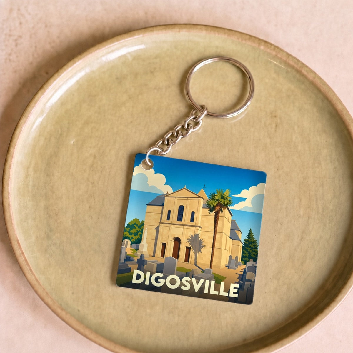 Porte-clés souvenir de la ville de Digosville avec une illustration stylisée d'une église et de son cimetière.
