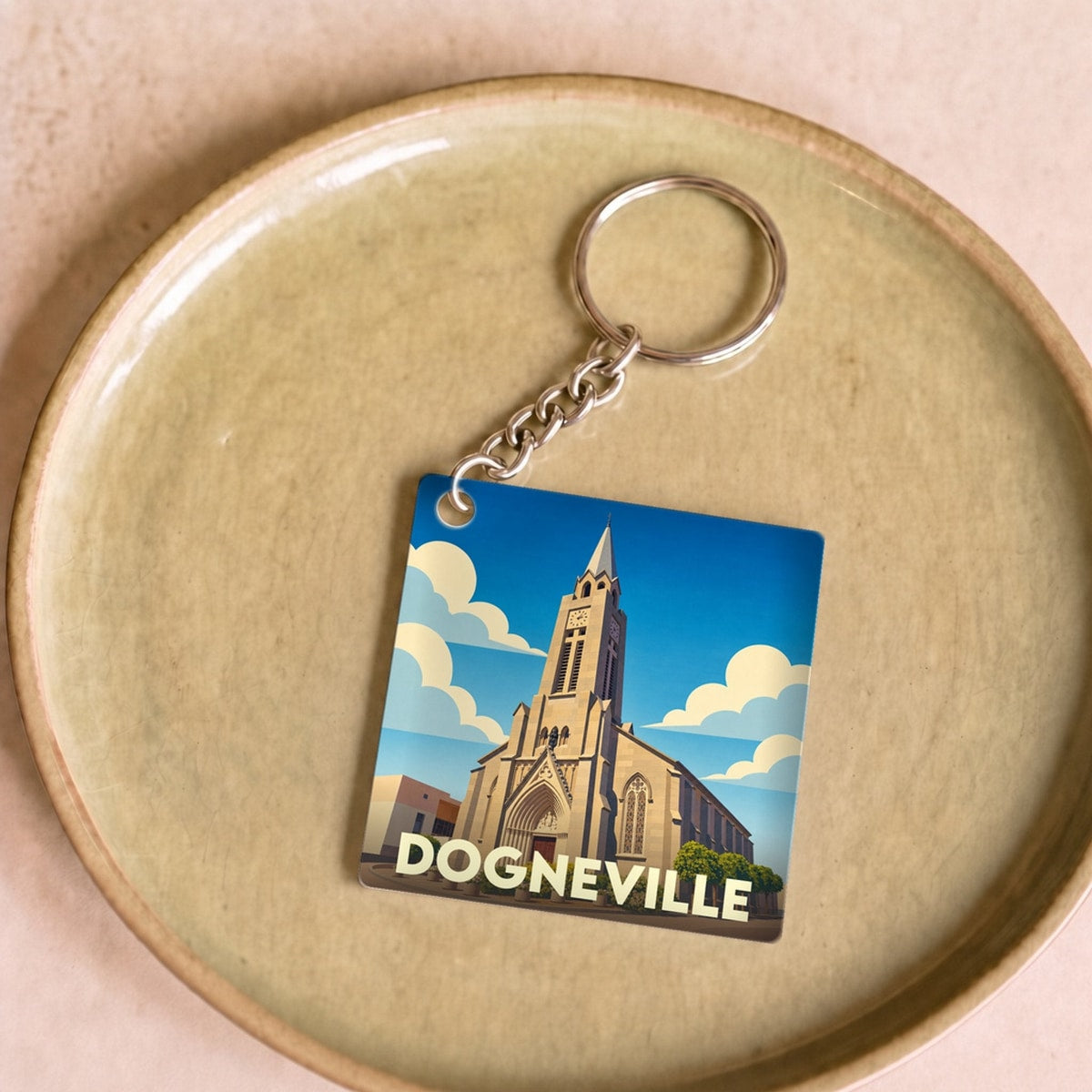 Porte-clés souvenir de la ville de Dogneville avec une illustration stylisée de son église.