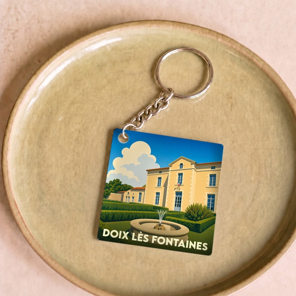 Porte-clés souvenir de la ville de Doix lès Fontaines avec une illustration stylisée d'un domaine et de sa fontaine.