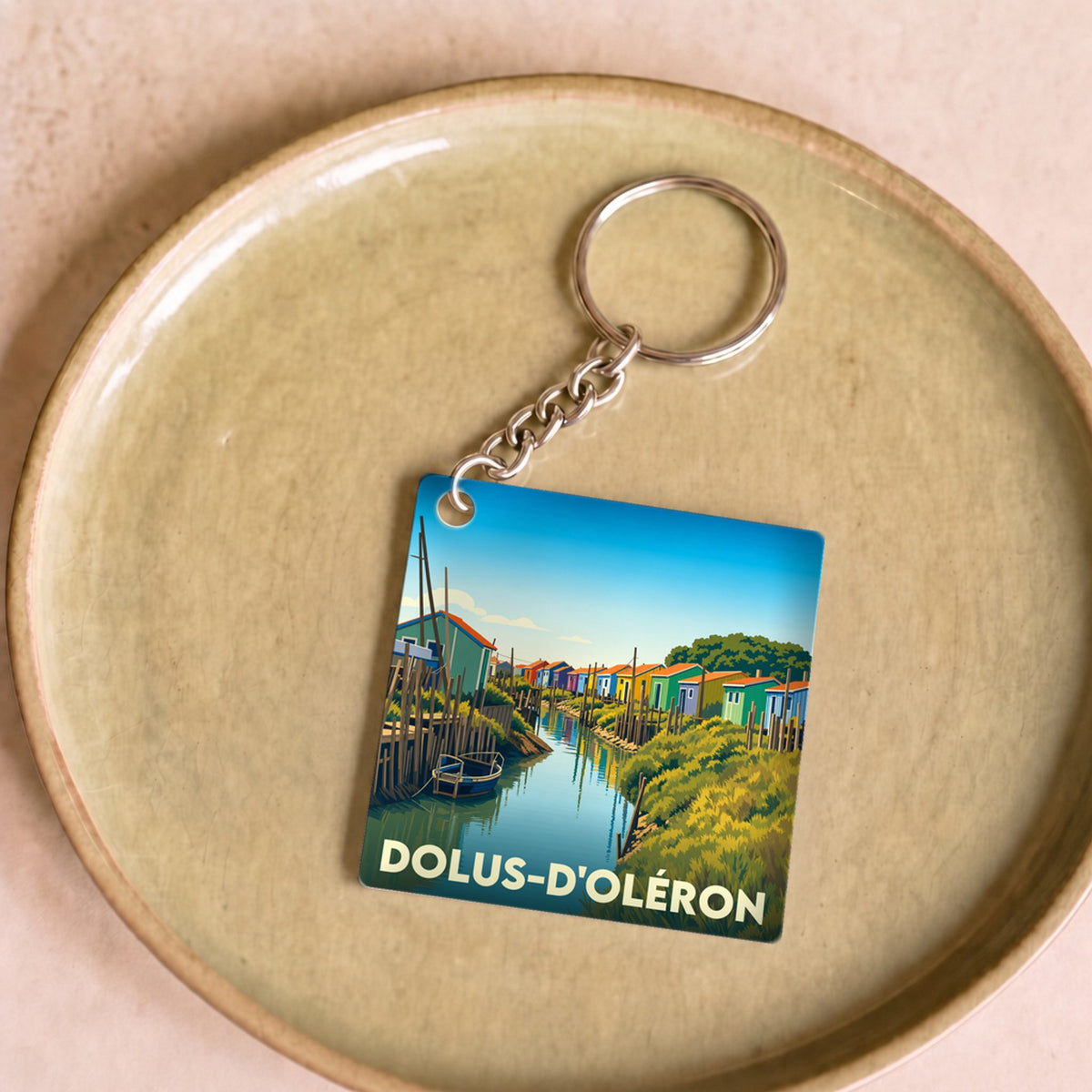 Porte-clés souvenir de la ville de Dolus-d'Oléron avec une illustration stylisée de cabanes de pêcheurs colorées.