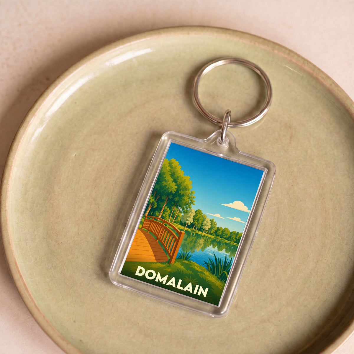 Porte-clés souvenir de la ville de Domalain avec une illustration stylisée de son étang.